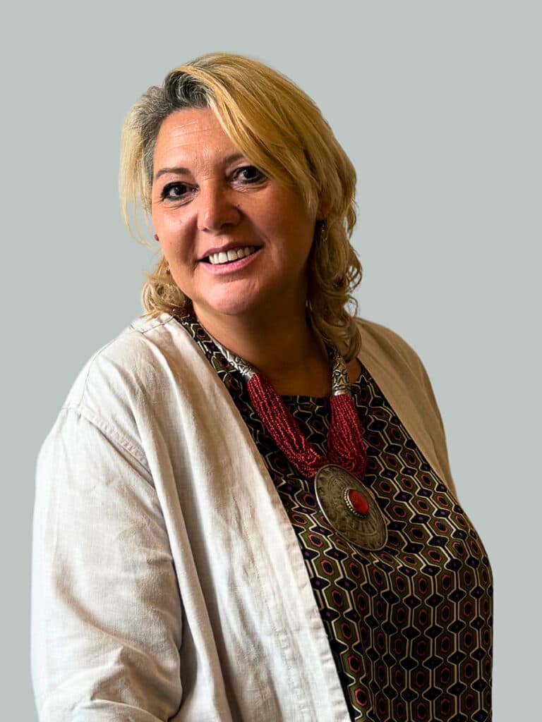 Ritratto di Paola Chiesa con capelli biondi, camicia chiara e collana vistosa
