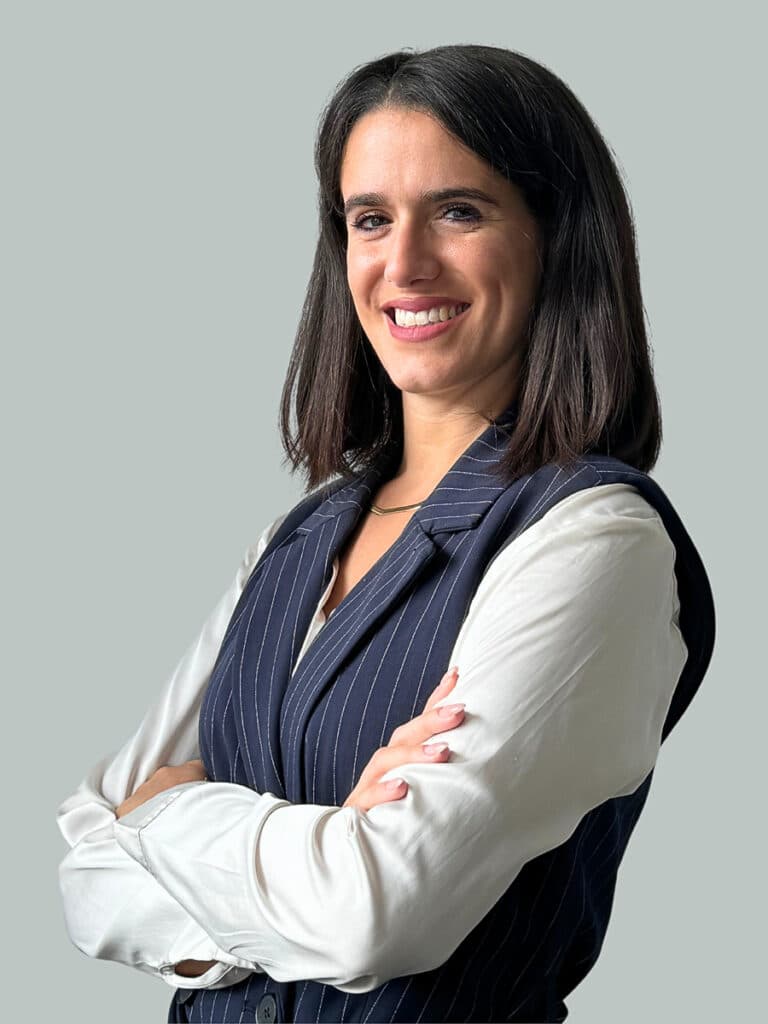 Giulia Pagliacci sorride con le braccia incrociate, indossando un completo gessato blu