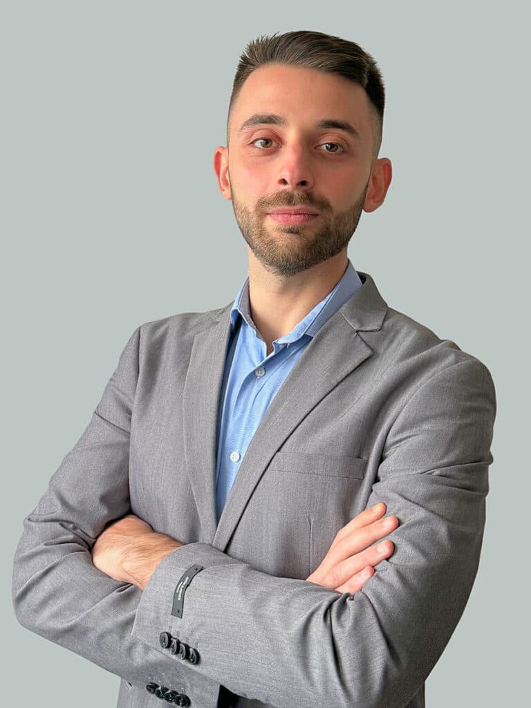 Samuele Lepera in posa con le braccia incrociate, indossa giacca grigia e camicia azzurra
