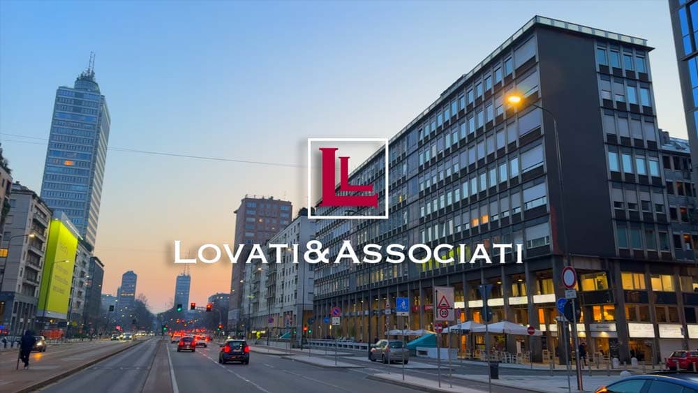 Strada cittadina al tramonto con grattacieli, traffico e logo Lovati & Associati