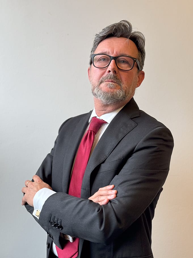 Ritratto di Luca Lovati in abito scuro e cravatta rossa, con le braccia incrociate